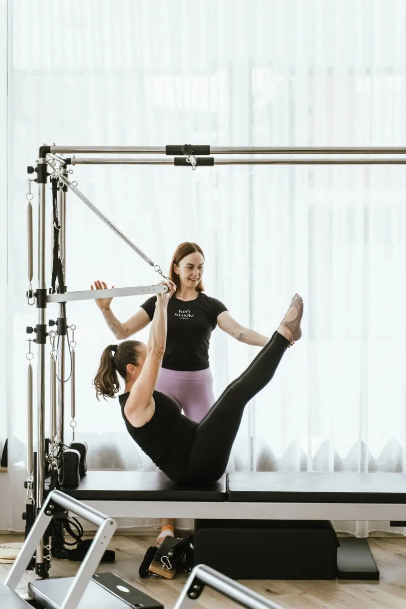A Kefi Studio trainer guiding a client through a clinical Pilates session on the Cadillac