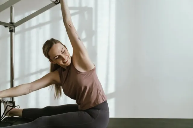 A Kefi client smiling through a stretch on the Pilates tower